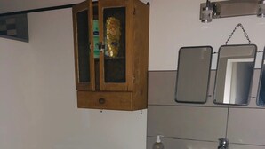 Een kleine badkamer met toilet, wastafel, kast en spiegel.