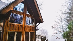 A wooden cabin with large windows and a steeply pitched roof.