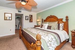 A bedroom with a wooden bed, a ceiling fan, a nightstand, and a bedside table. - Sea Winds 56 Beachside Retreat (St. Augustine)