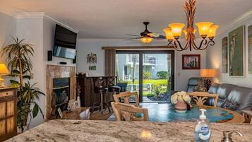 A spacious living area with a large dining table, a fireplace, and a view of the outdoors.