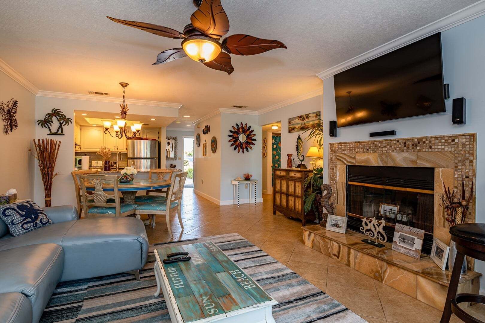 A spacious living room with a fireplace, a ceiling fan, and a dining area.
