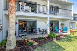 A two-story residential building with a covered patio, outdoor seating, and a visible kitchen area. - Sea Winds 56 Beachside Retreat (St. Augustine)