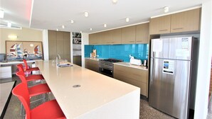 A modern kitchen with a central island, stainless steel appliances, and a blue backsplash.