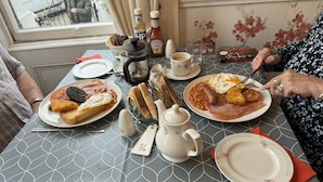 A dining table with plates of food, a teapot, and condiments. - White Court Llandudno (Llandudno)