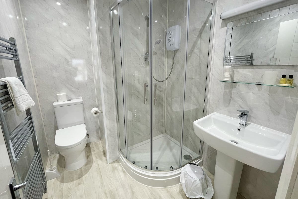 A modern bathroom with a glass-enclosed shower, a toilet, and a sink with a mirror above it.