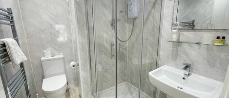 A modern bathroom with a glass-enclosed shower, a toilet, and a sink with a mirror above it.