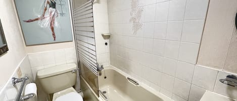 A bathroom with a bathtub, toilet, sink, and a painting on the wall.