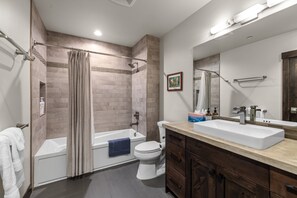 Een moderne badkamer met een badkuip, toilet en wastafel.