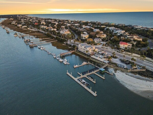 An aerial view of a coastal town with a marina, residential buildings, and a beach.