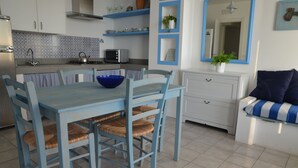 Uma cozinha moderna com armários azuis, uma mesa de jantar com cadeiras de vime, um micro-ondas e um fogão.
