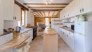 Una cucina spaziosa con travi in legno, mobili bianchi e un'isola centrale.