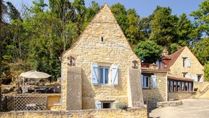Un edificio in pietra con tetto a punta, persiane bianche e una piccola finestra.