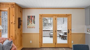 A cozy room with wooden walls and a large sliding glass door leading to a snowy deck. - Brand New Kitchen & Bathrooms, close to Mt Snow! (Dover)