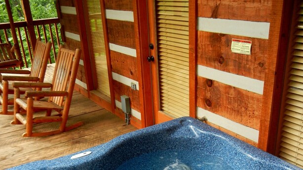Eine Holzterrasse mit Schaukelstühlen, einem Whirlpool und einem Schild mit der Aufschrift 'Cabin'.