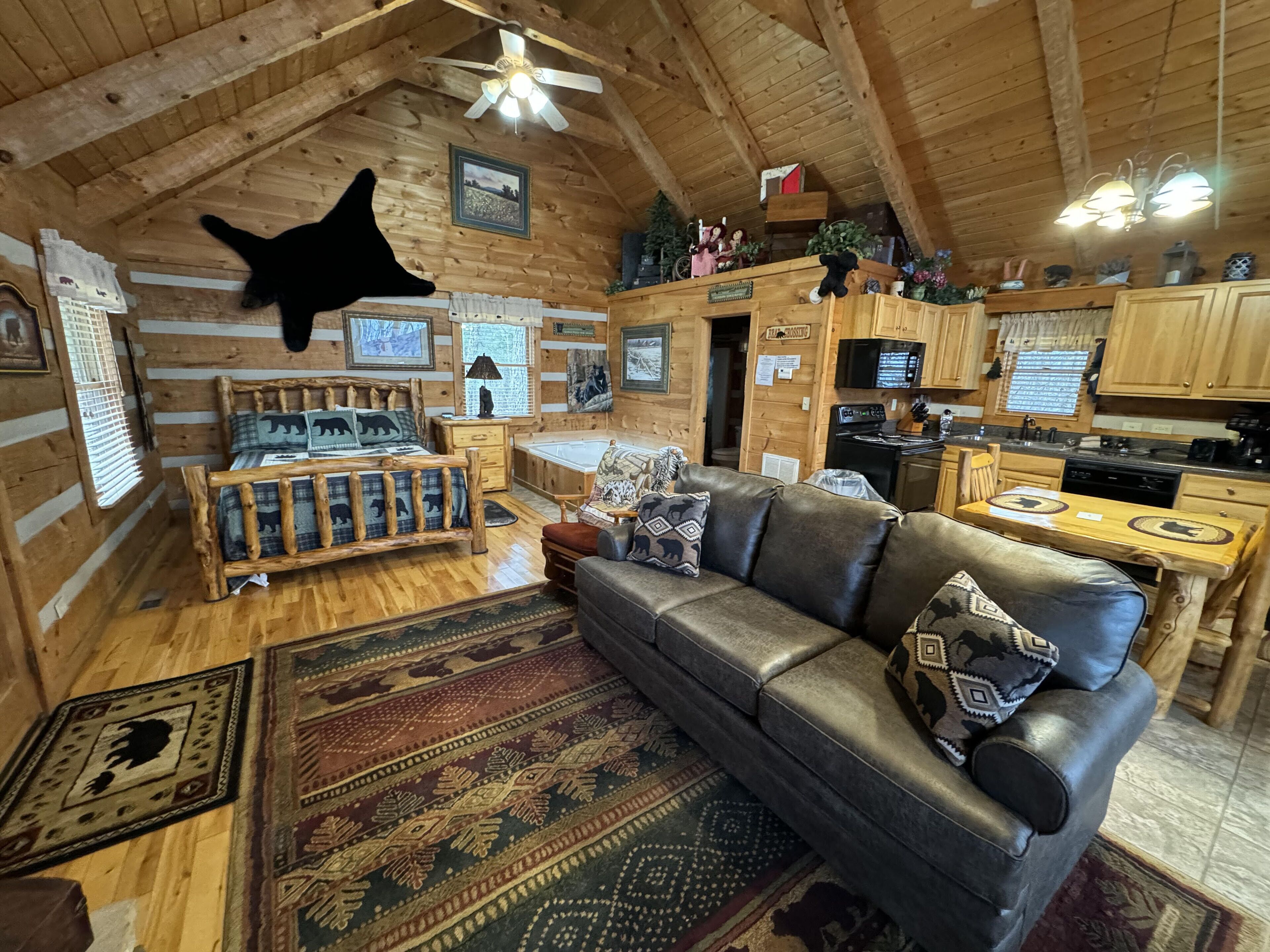 A log cabin interior with a living room, kitchen, and a ceiling fan.