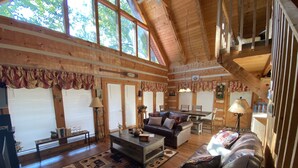 Ein geräumiges Wohnzimmer mit hohen Decken, Holzwänden und großen Fenstern.