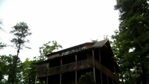 Un bâtiment rustique en bois, doté d’un balcon et entouré d’arbres.