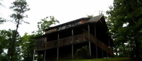 A rustic wooden building with a balcony, surrounded by trees.
