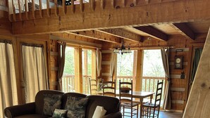 L’intérieur chaleureux d’un chalet avec un plancher en bois, un canapé, une table à manger et des chaises.