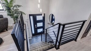 A modern staircase with a black railing, a potted plant, and a mirror on the wall. - Modern home with privacy of the hills right in town! (Rapid City)