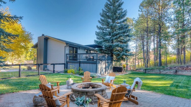 A patio with outdoor furniture, a fire pit, and a view of a house with a deck. - Modern home with privacy of the hills right in town! (Rapid City)