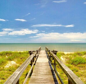 A wooden boardwalk leading to a beach with clear skies and calm waters. - Perfect Getaway for Family Beach Vacation (Jacksonville Beach)