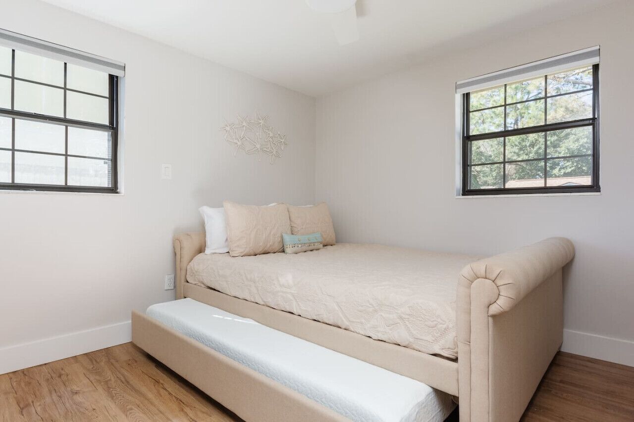 A bedroom with a bed, two windows, and a ceiling light.