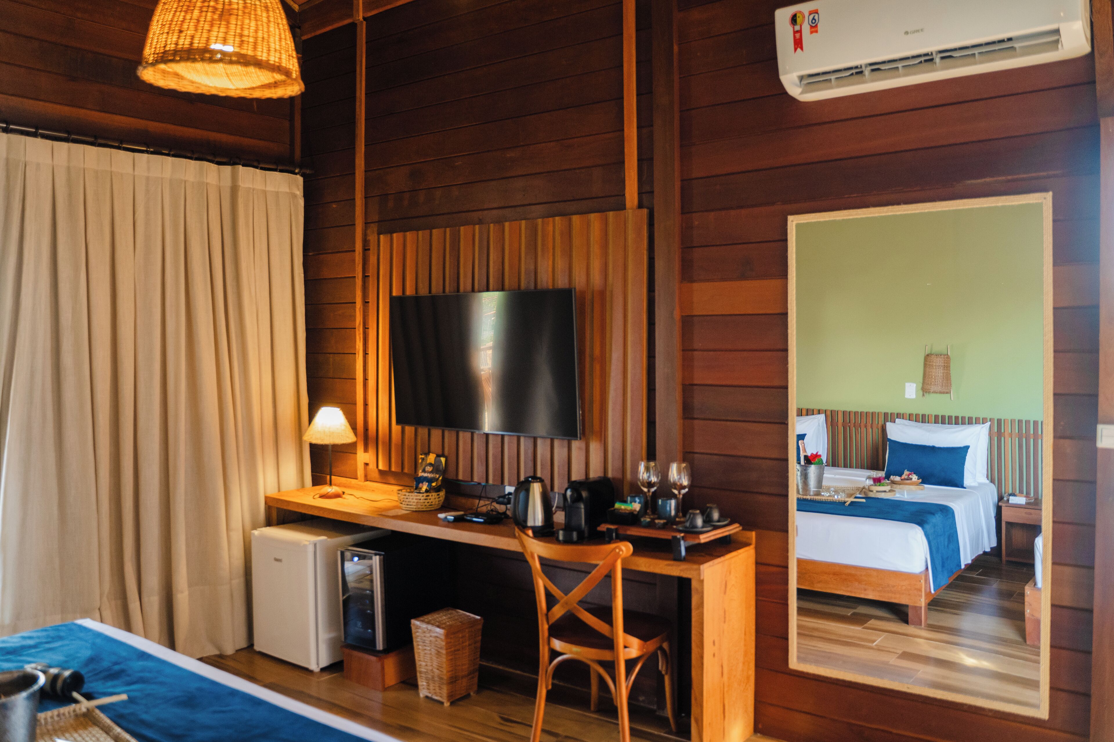 A cozy room with a bed, a desk, a television, and a small refrigerator.