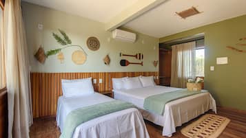 Une chambre avec deux lits, un lambris en bois, un tapis tissé et des éléments décoratifs sur les murs, notamment une fougère et un objet tissé de forme circulaire.