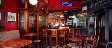 A bar area with wooden furniture, a bar counter, and various signs including one for Waverley Cigarettes.