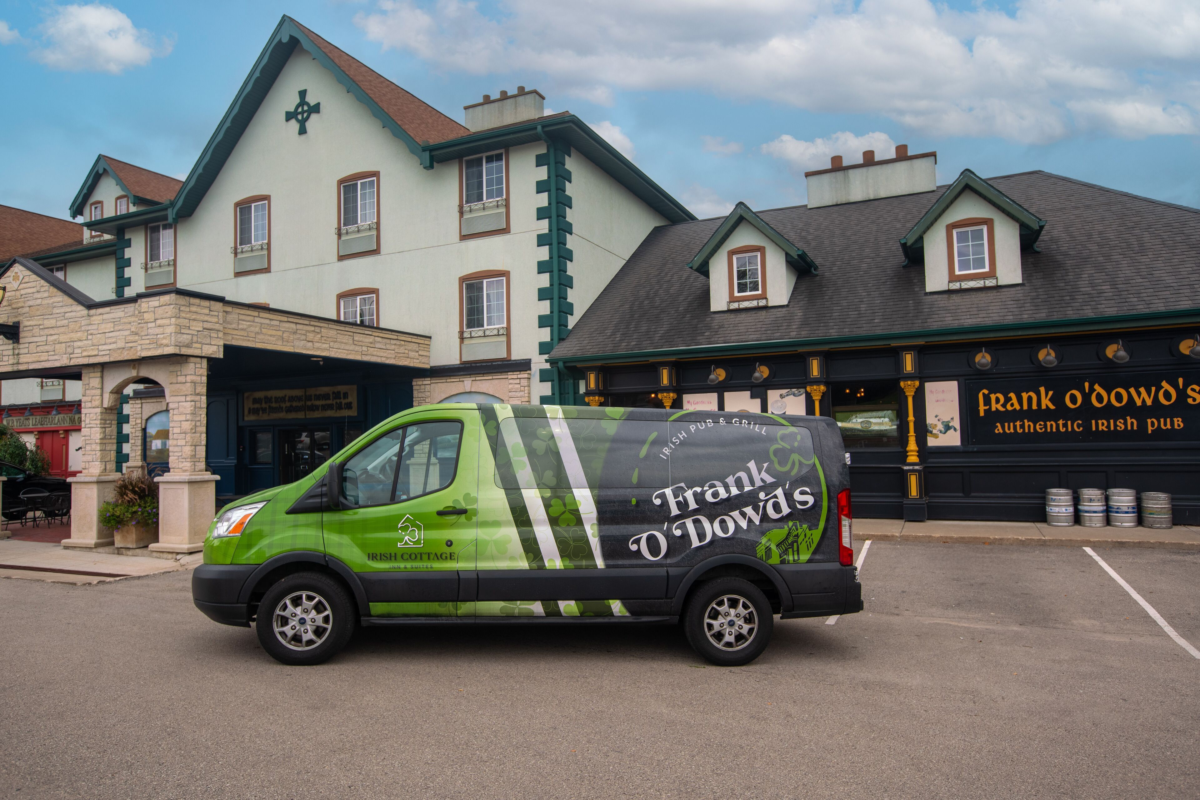 A green van parked in front of a building with a sign reading "Frank O'Dowd's authentic Irish Pub."