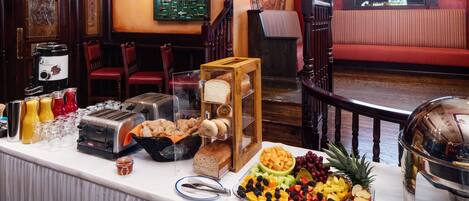 A buffet setup with various food items, a coffee machine, and a seating area with a view.