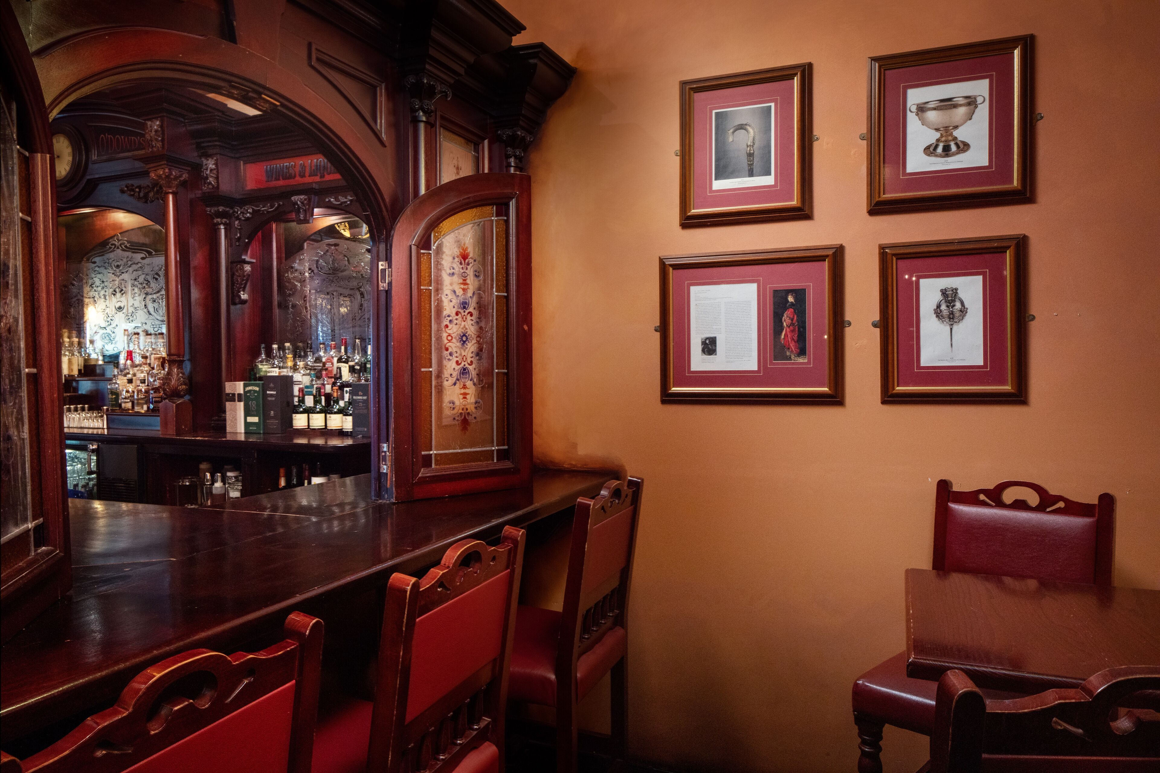 A bar area with wooden furniture, framed pictures on the wall, and a bar counter.