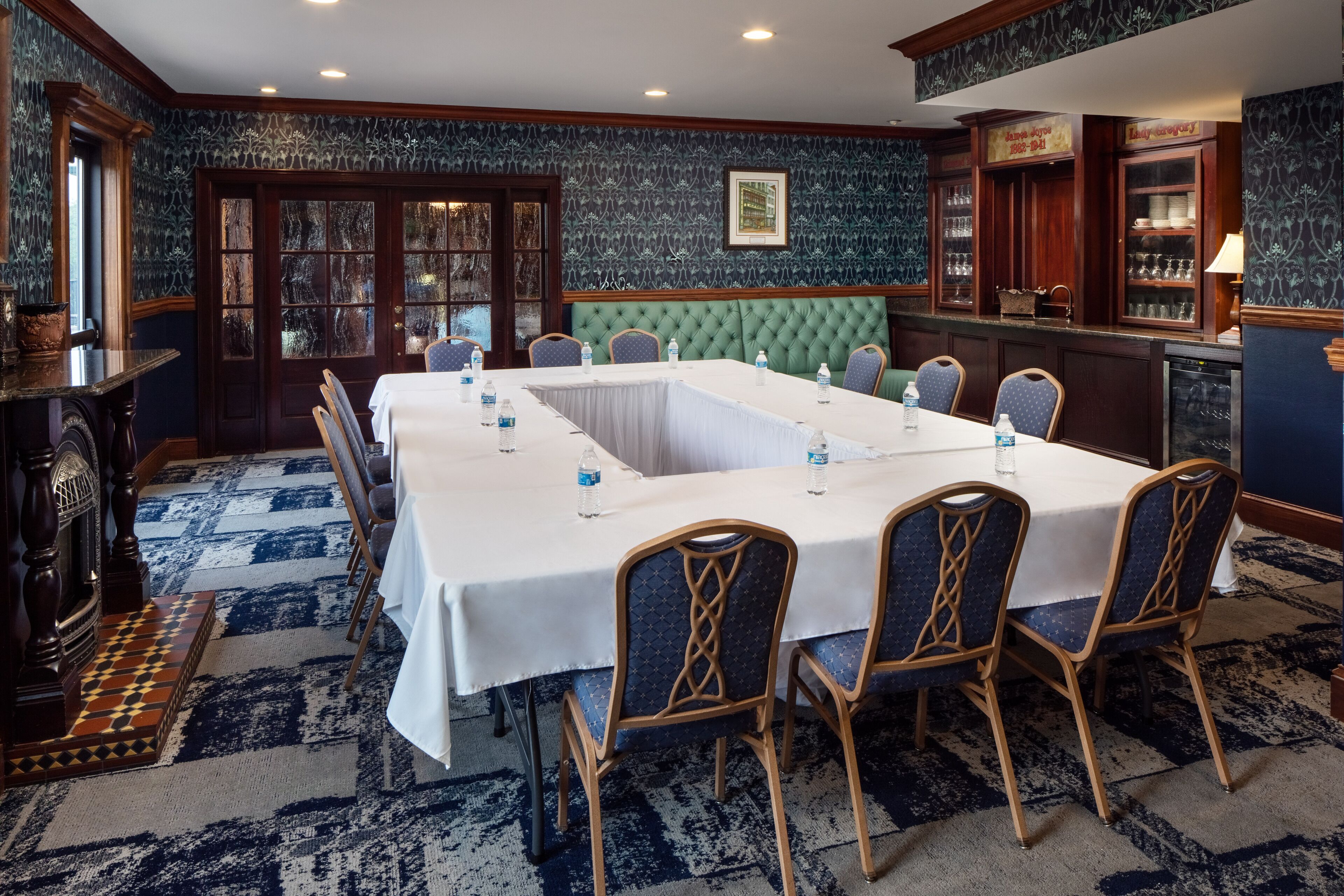 A conference room with a long table, chairs, and a green upholstered bench.