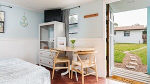 Une chambre à coucher avec un lit, un bureau, deux chaises, une télévision et une fenêtre.