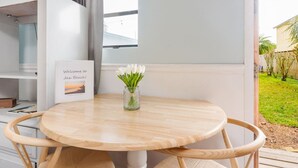 Une table ronde en bois, sur laquelle est posé un vase en verre rempli de fleurs blanches, et un panneau d’accueil encadré.