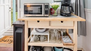 Un coin cuisine équipé d’un four à micro-ondes, d’une machine à café et d’étagères de rangement.