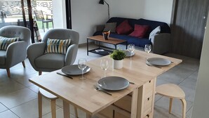 Ein Essbereich mit einem Holztisch, gedeckt für vier Personen, zwei grauen Stühlen und einem kleinen Blumentopf.