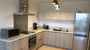 Eine moderne Küche mit integriertem Mikrowellenherd, Backofen, Spüle und einem Edelstahlkühlschrank.