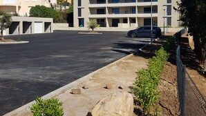 Ein mehrgeschossiges Gebäude mit Parkplatz davor, umgeben von Grünflächen und blauem Himmel.