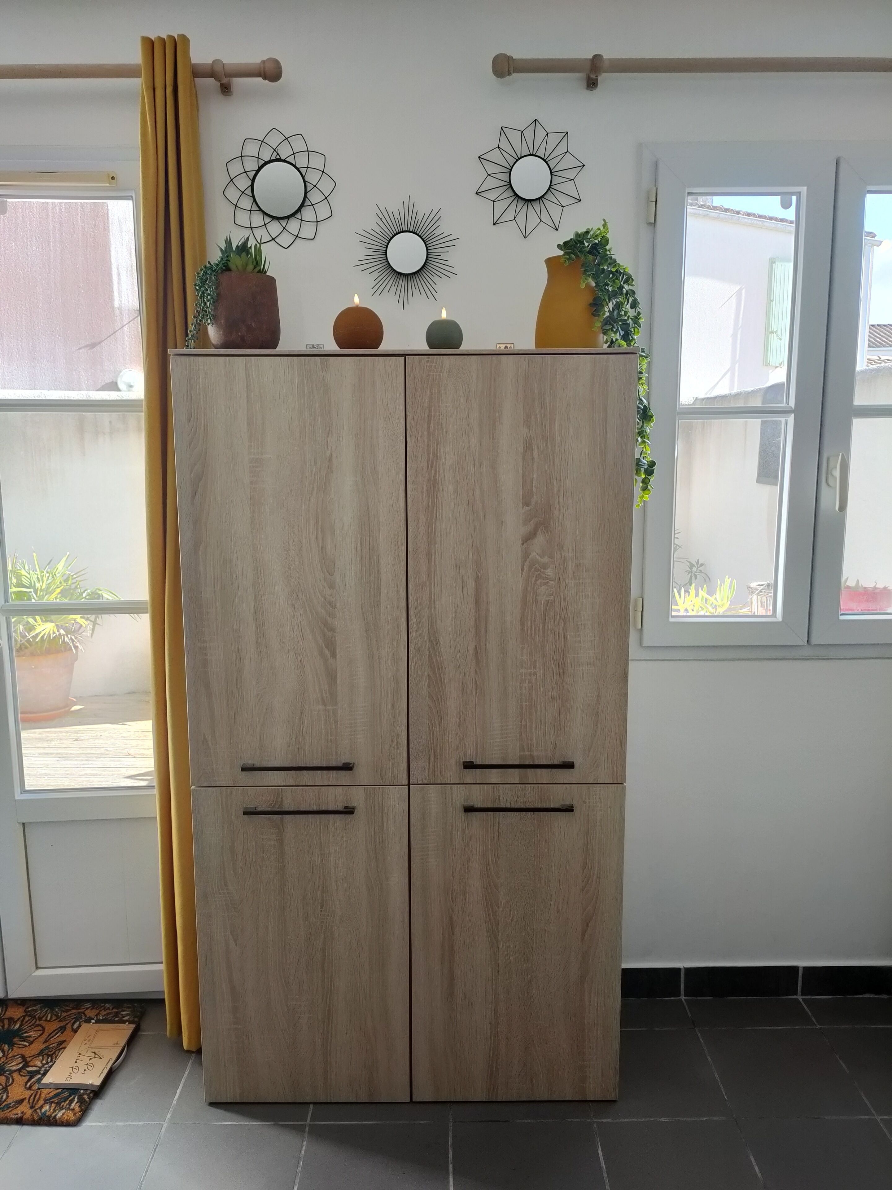 A wooden wardrobe with two doors, a curtain, and decorative wall art.