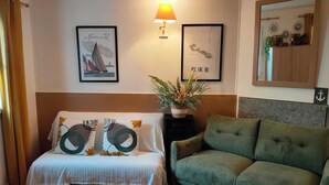 A cozy room with a bed, a green sofa, a small table with a plant, and a lamp. - Maison Dans Résidence Avec Piscine "jetez L'ancre" (La Flotte)
