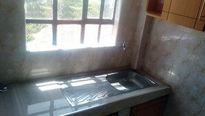 Eine Küche mit Fenster, Spüle und Holzschränken.