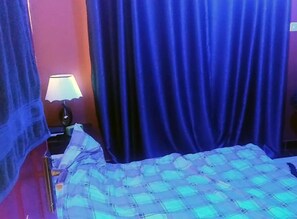 Relax in a comfortable room with a bed, nightstand, and wall-mounted shelf.