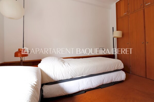 A bedroom with a bed, a wardrobe, and a lamp.