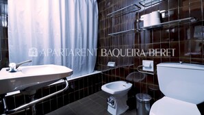 Een moderne badkamer met een witte wastafel, toilet en bidet.
