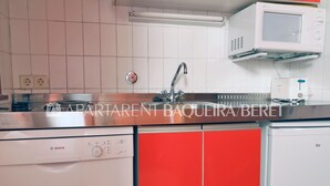 Eine Küche mit einem Geschirrspüler von Bosch, einem roten Schrank, einer Spüle und einer Mikrowelle.