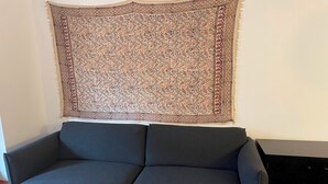 Un canapé gris foncé, sur lequel est posé un tapis à motifs chevrons.