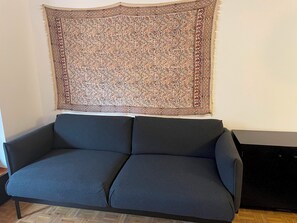 Un canapé gris foncé, sur lequel est posé un tapis à motifs chevrons.