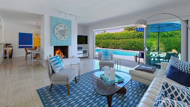 Una sala de estar moderna con chimenea, vista a la piscina y comedor.